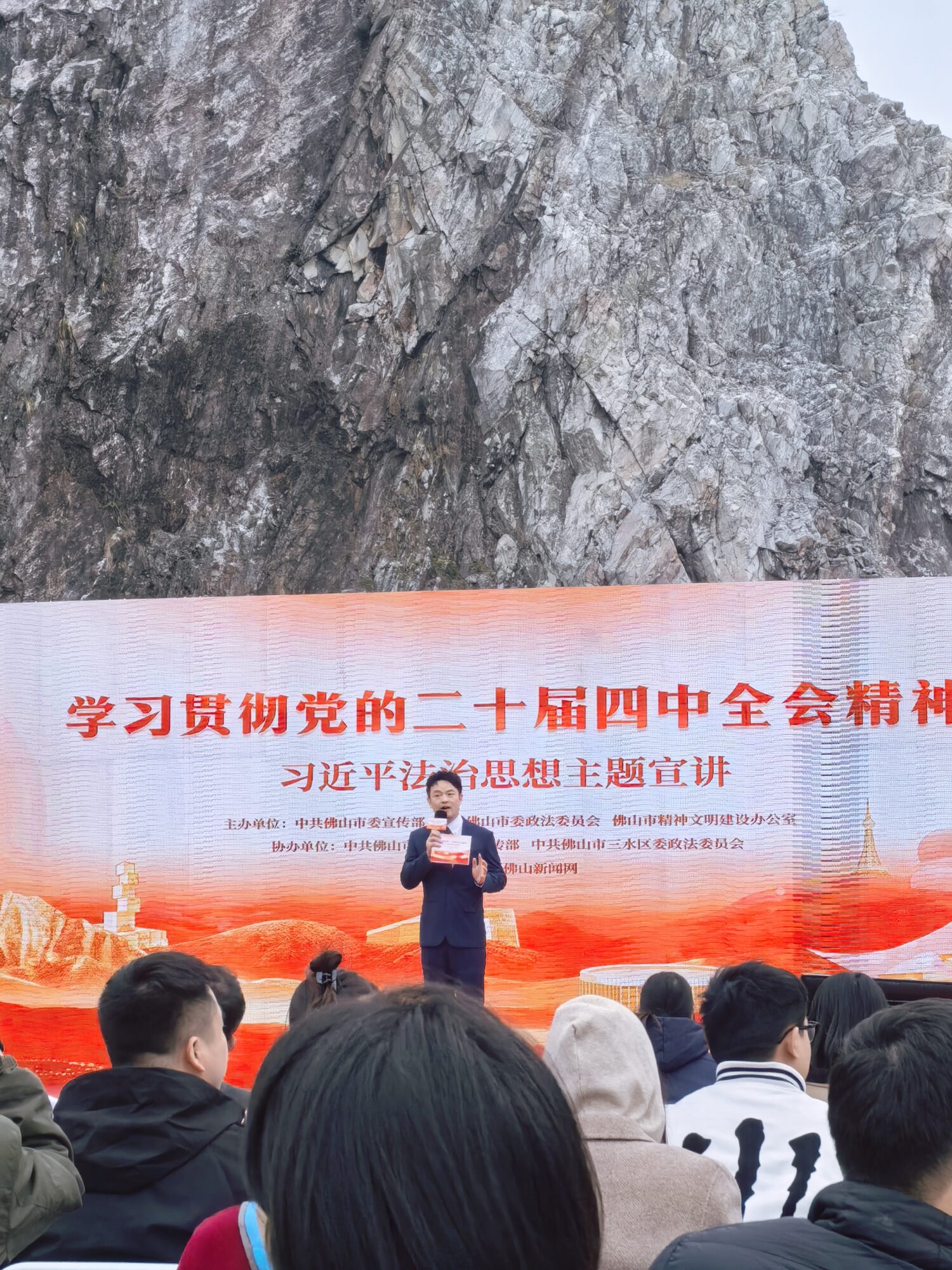 常安在主题宣讲现场主持，背景为矿坑崖壁与LED主题主屏