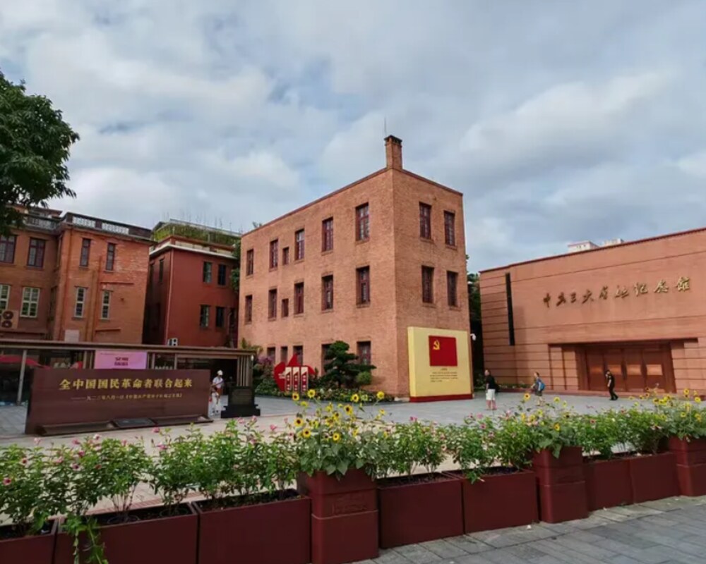 中共三大会址纪念馆门前广场：红砖建筑群与馆名门头，左侧为「全中国国民革命联合起来」标语墙（中共三大会址纪念馆实地照片）